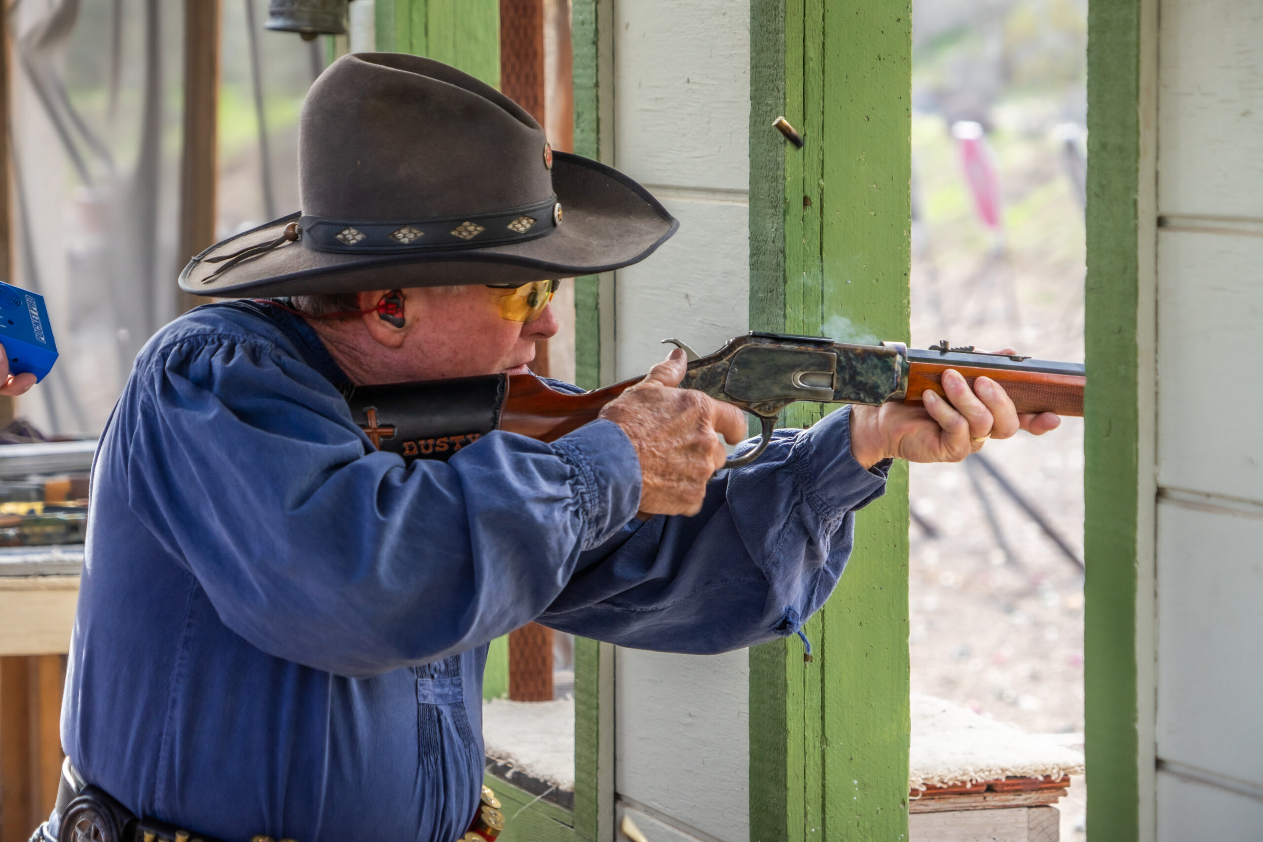 Cowboy action shooter firing lever-action rifle at Cowtown Range, Peoria, Arizona.