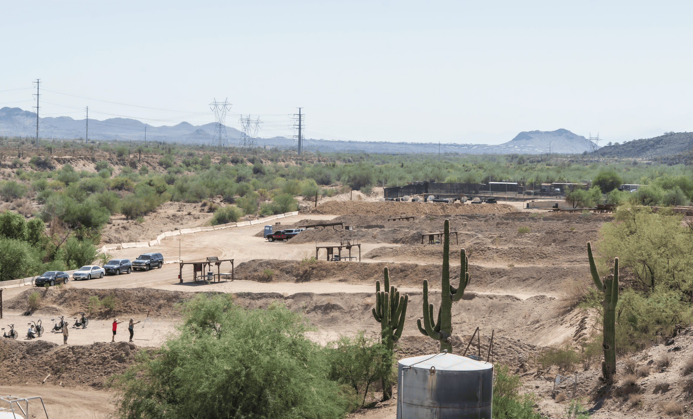 High-angle scenic view of the expansive outdoor shooting bays and high-desert terrain at Cowtown Range in Arizona, featuring saguaro cacti and distinct vehicle parking areas.