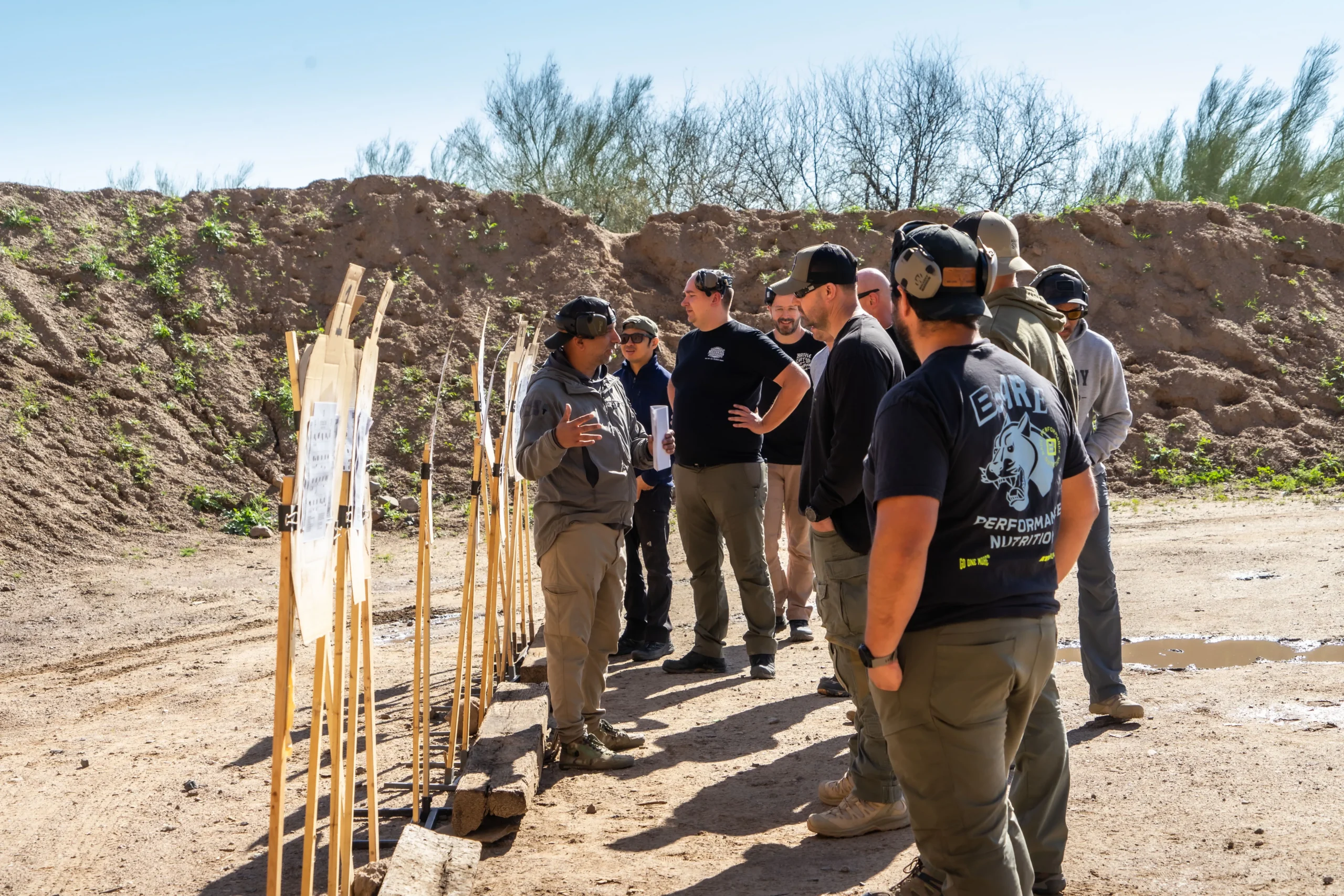 0284f27c-94c6-4e49-a22f-506b982a82fc.webp Instructors and shooters review paper targets during a training course on an outdoor bay at Cowtown Range.