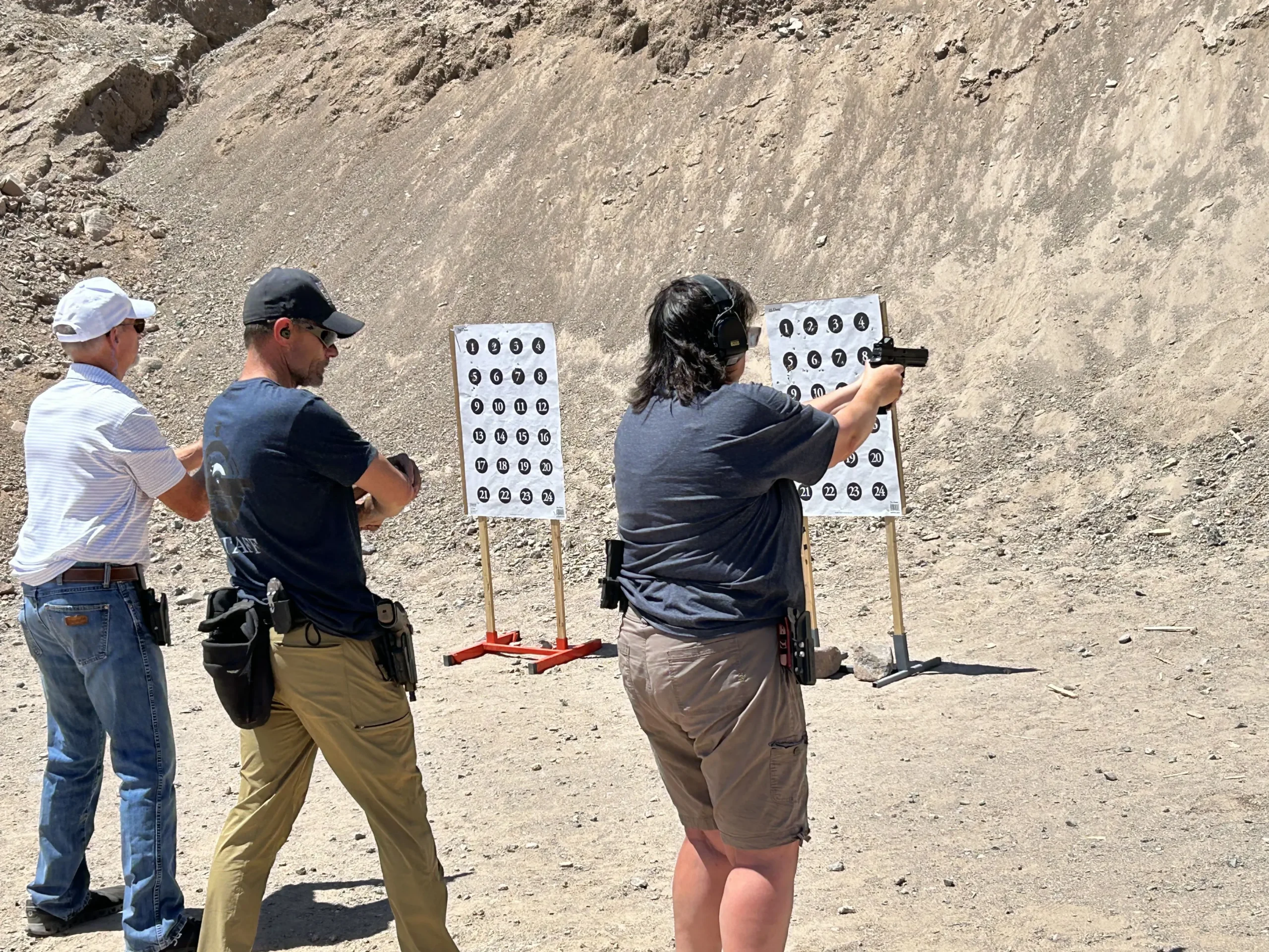 Female shooter practicing sight alignment and trigger control on dot targets during a pistol class.