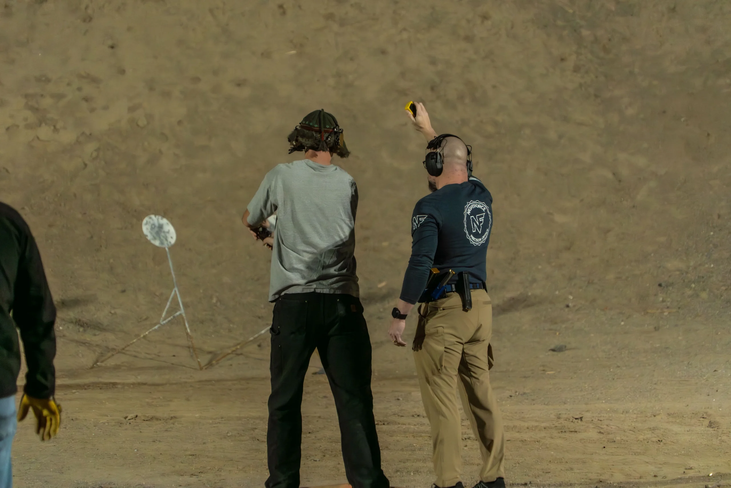 A Cowtown Range instructor monitors a shooter running low-light drill progressions on steel targets downrange.
