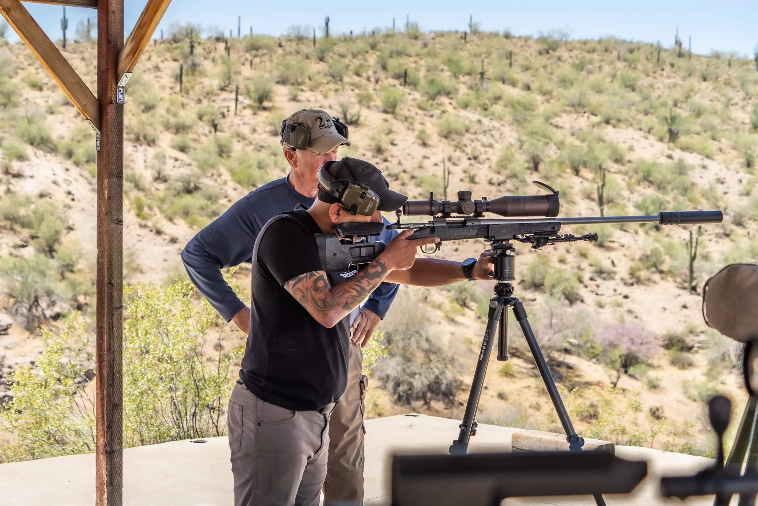 Shooter working a long-range precision rifle on a tripod with a spotter at Cowtown Range.