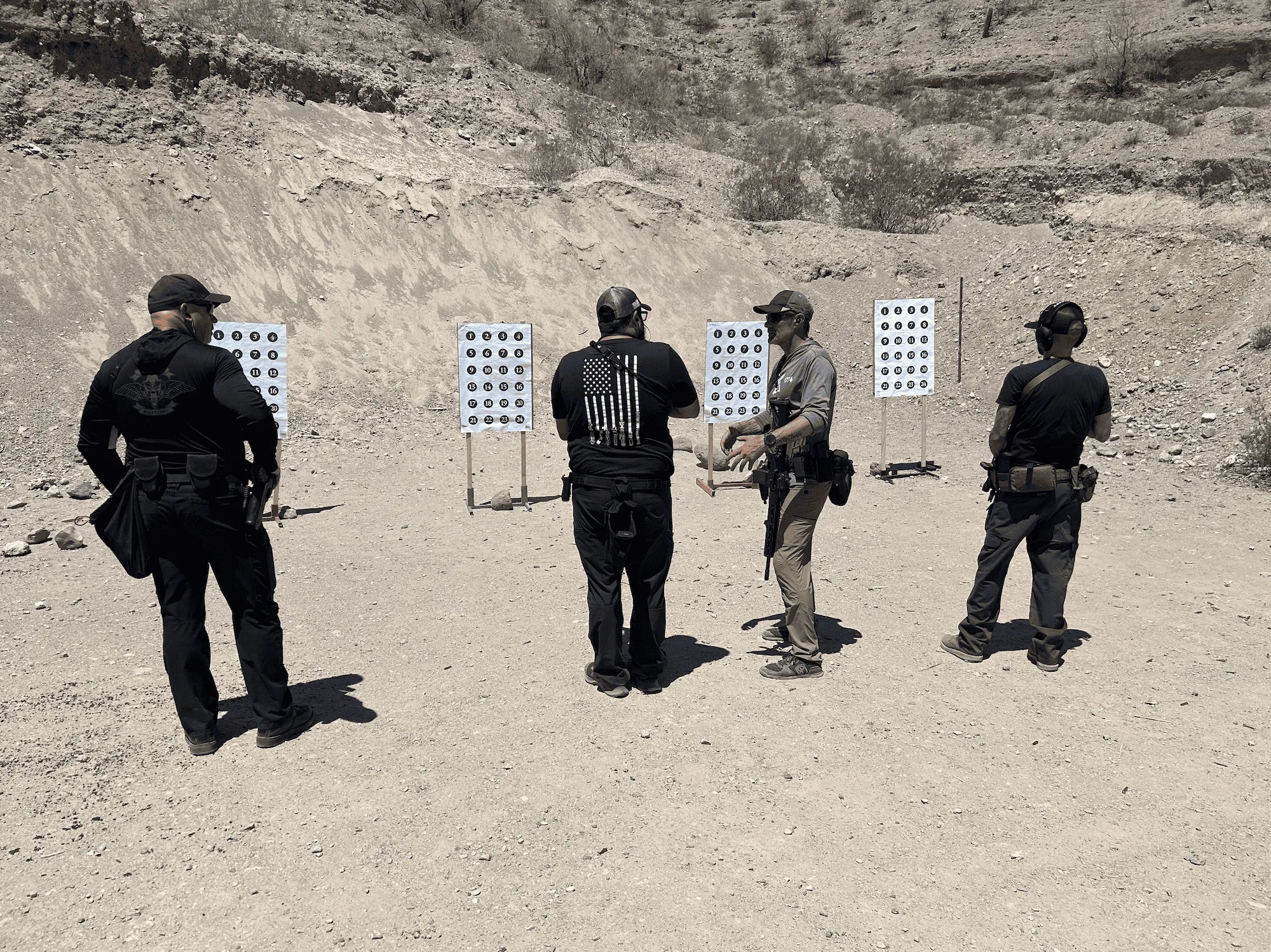 Instructors and shooters discussing target placement and shot groups during a live-fire course on a high-desert range.