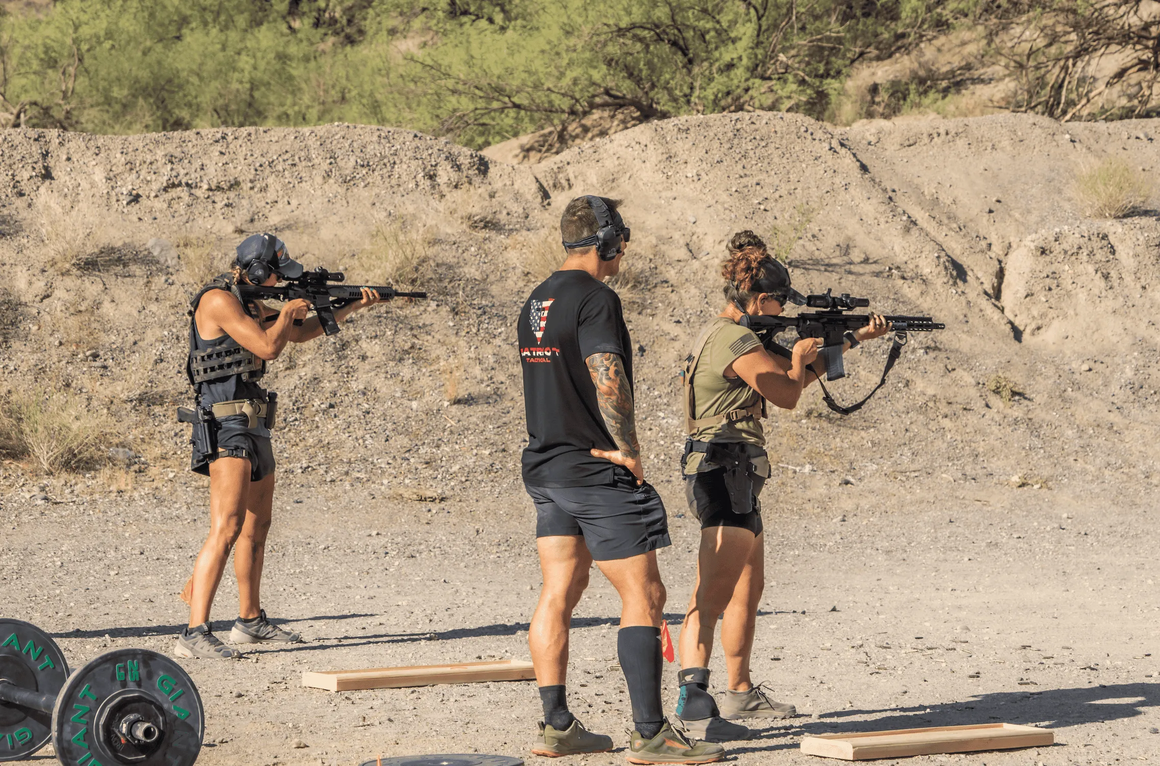 Tactical Games competitors in a live-fire rifle drill next to barbell weights at Cowtown Range.