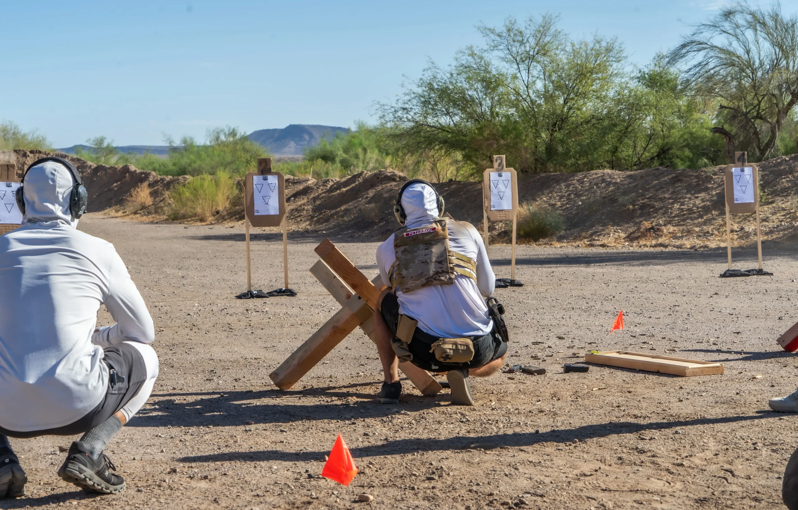A shooter practices positional drills behind a wooden barricade at an outdoor bay at Cowtown Range in Peoria, AZ.