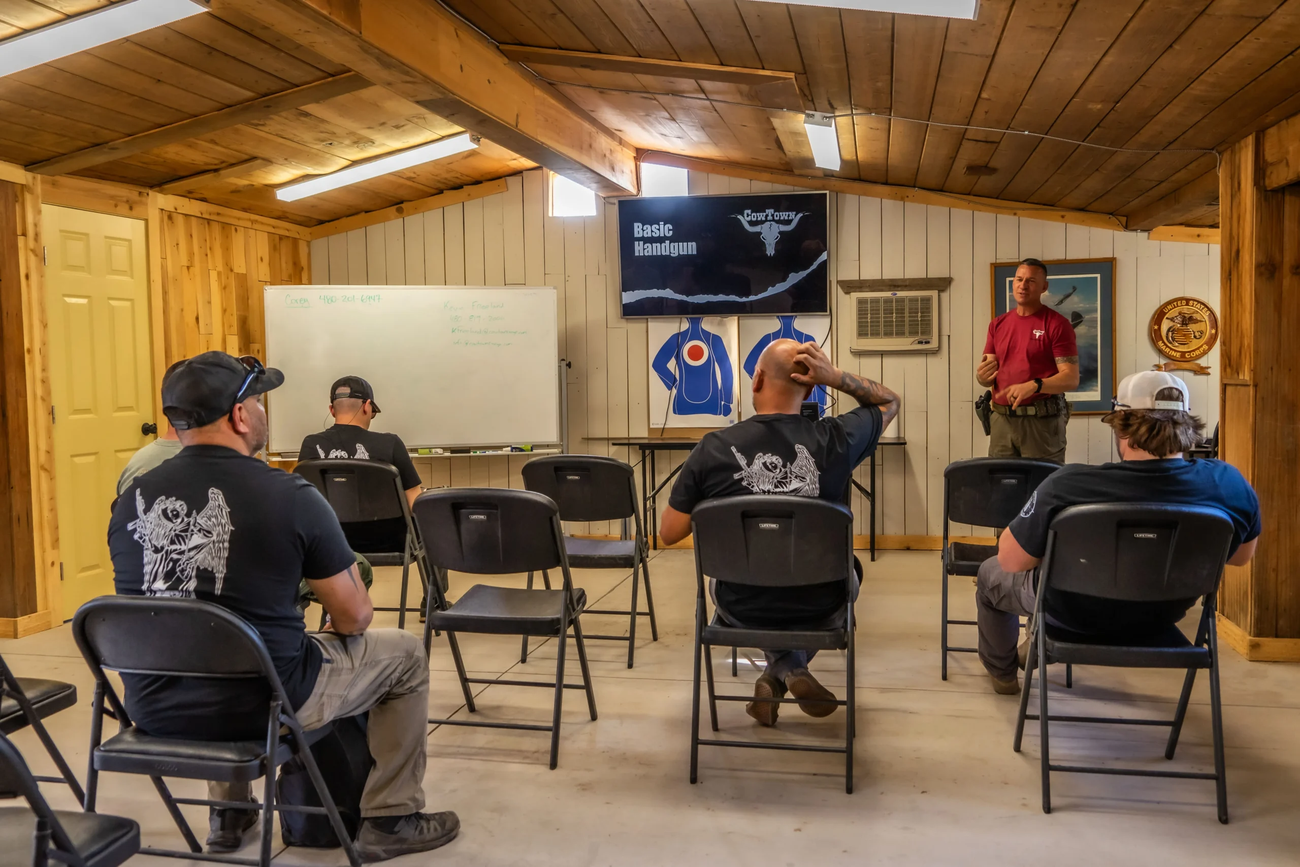 An instructor delivering the Basic Handgun classroom brief to students inside the Cowtown Range room.