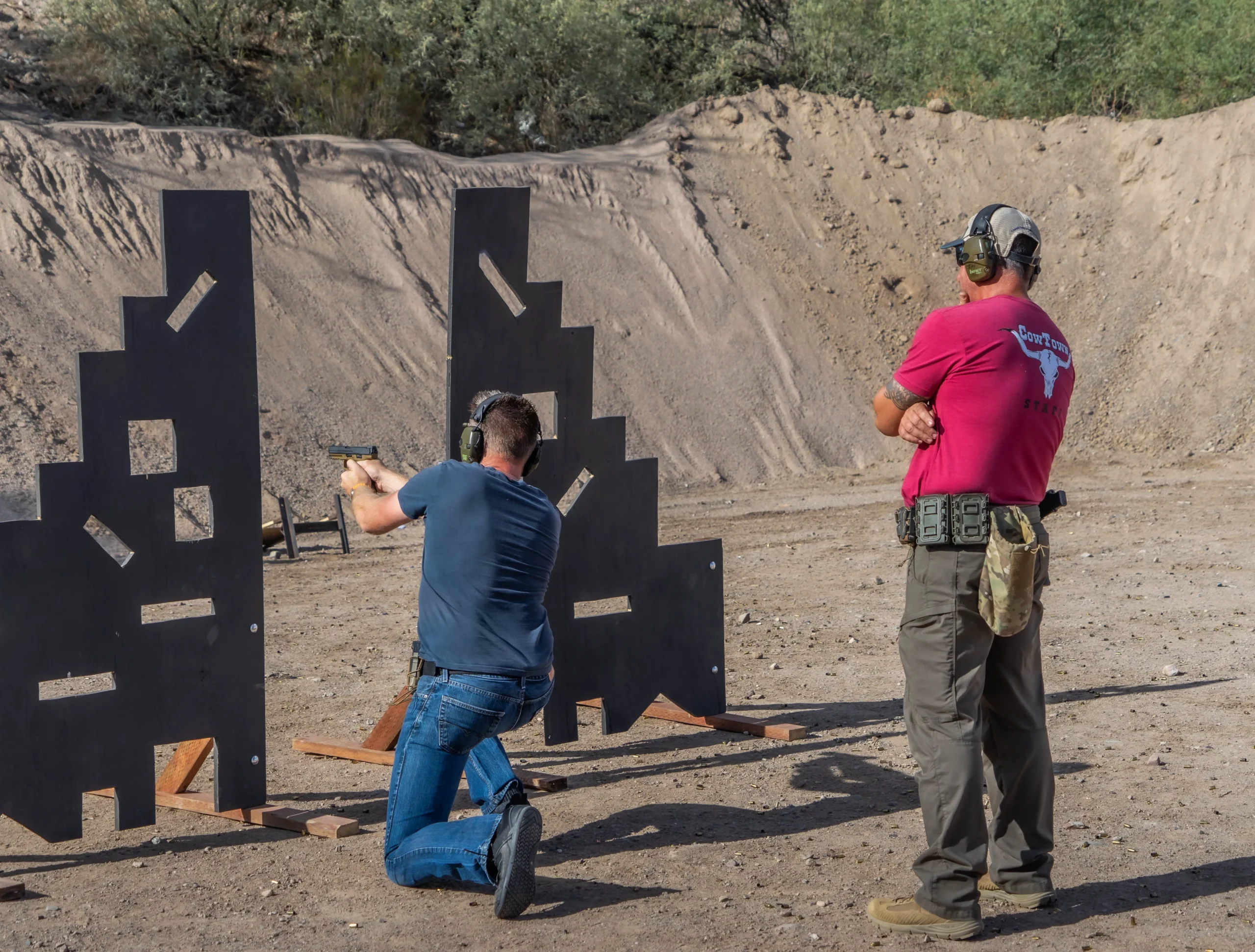 A Cowtown staff member observing a shooter executing a kneeling position drill behind a barricade.