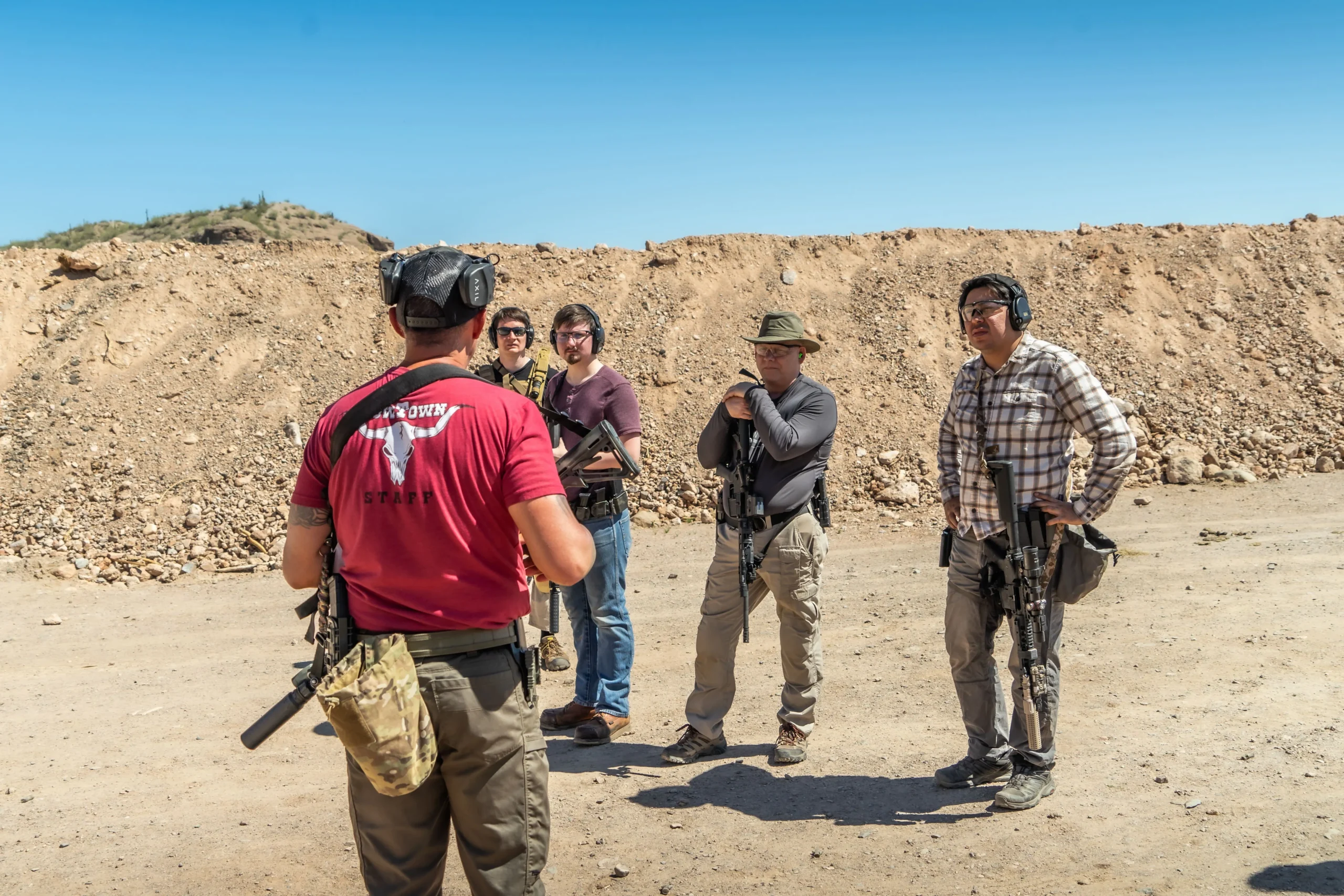 Cowtown instructor debriefing a squad of shooters wearing full platform gear between course runs.