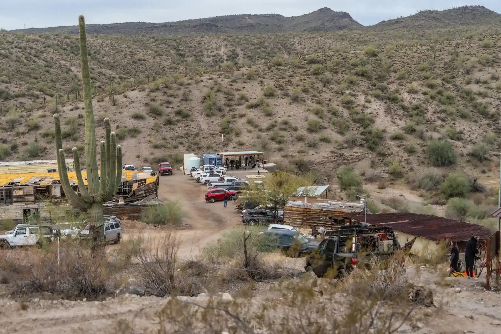 High-angle view of the rustic Cowtown Range complex, parking area, and shooting bays set against desert hills.